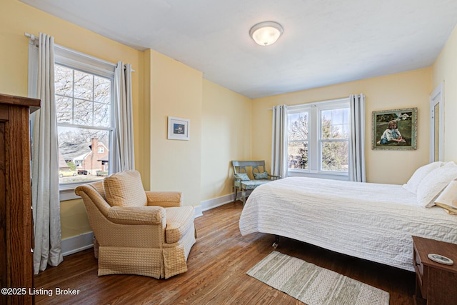 bedroom with baseboards, multiple windows, and wood finished floors