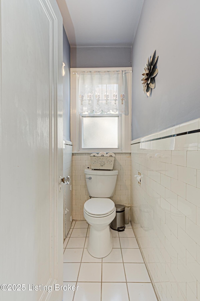 bathroom featuring tile walls, toilet, tile patterned floors, and wainscoting