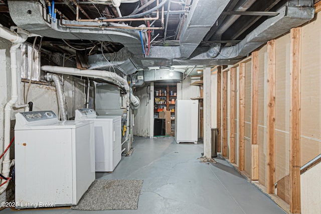 unfinished below grade area featuring separate washer and dryer and freestanding refrigerator
