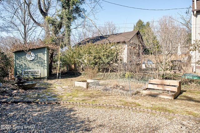 view of yard featuring a garden, an outbuilding, fence, and a shed