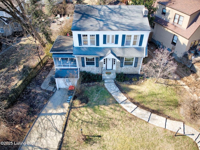 view of front facade featuring fence, an attached garage, stone siding, driveway, and a front yard