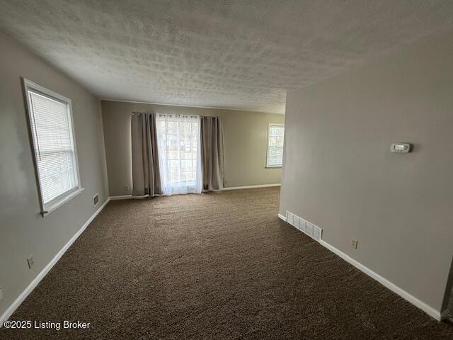 empty room featuring baseboards, visible vents, a textured ceiling, and carpet flooring