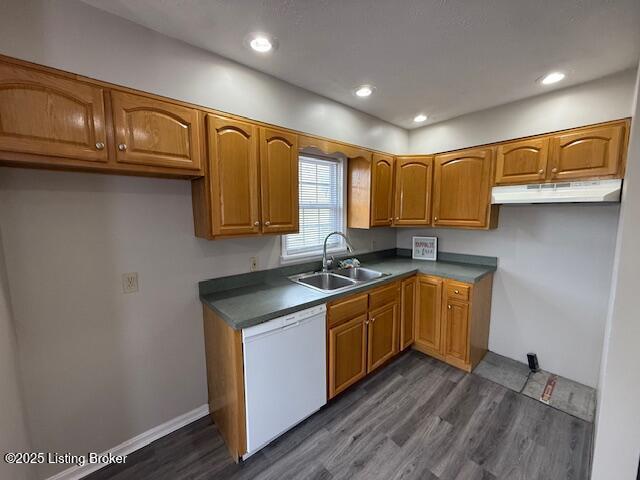 kitchen with brown cabinetry, white dishwasher, under cabinet range hood, and a sink