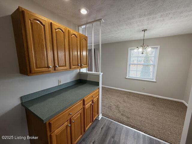 kitchen with a textured ceiling, dark countertops, baseboards, and brown cabinets