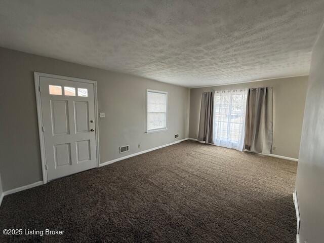 entrance foyer with visible vents, dark carpet, a textured ceiling, and baseboards