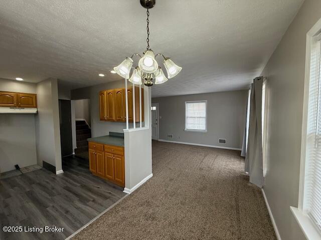 kitchen with brown cabinets, visible vents, open floor plan, a textured ceiling, and baseboards