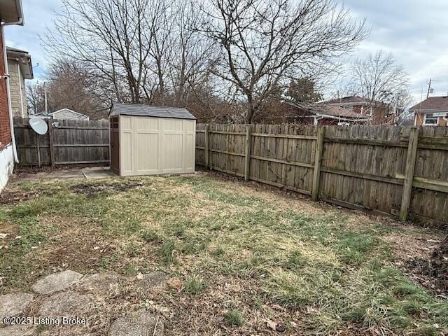 view of yard with a storage shed, a fenced backyard, and an outbuilding