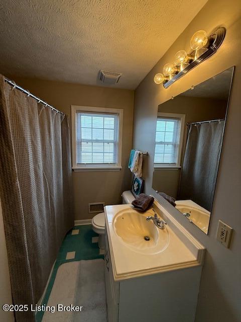 full bathroom featuring visible vents, vanity, toilet, and a textured ceiling