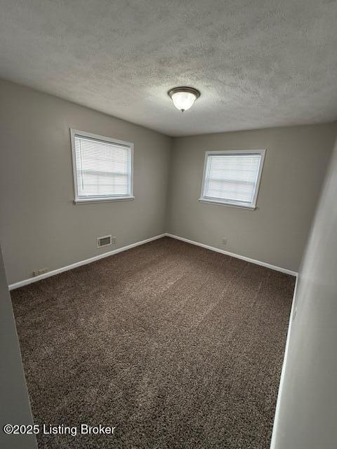 unfurnished room featuring a textured ceiling, carpet flooring, visible vents, and baseboards