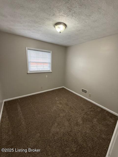 unfurnished room featuring dark colored carpet, visible vents, a textured ceiling, and baseboards