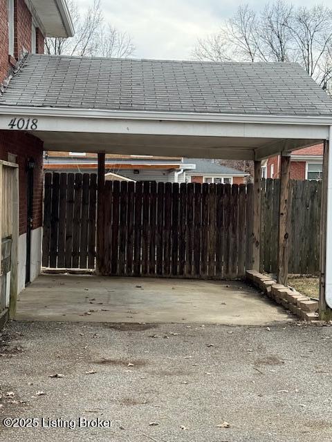 view of parking / parking lot with a carport and fence