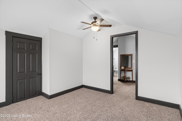 carpeted spare room with lofted ceiling, ceiling fan, and baseboards