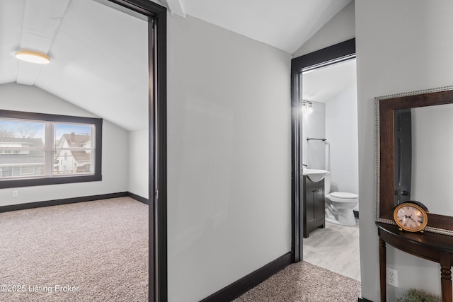 corridor featuring vaulted ceiling, carpet, and baseboards