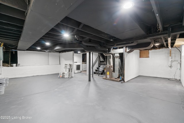 unfinished basement featuring heating unit, stairs, and washer / clothes dryer