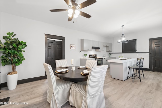 dining area with ceiling fan, light wood finished floors, and baseboards