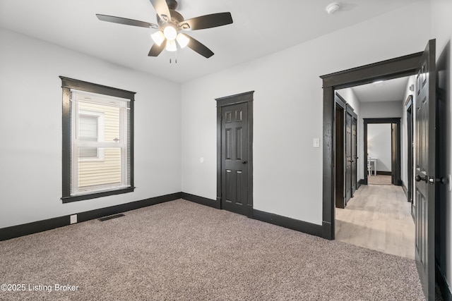 unfurnished room with a ceiling fan, light colored carpet, visible vents, and baseboards