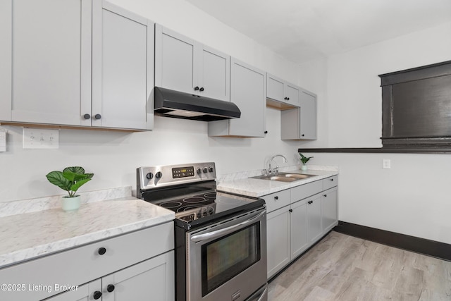 kitchen featuring stainless steel electric range oven, light wood finished floors, a sink, under cabinet range hood, and baseboards