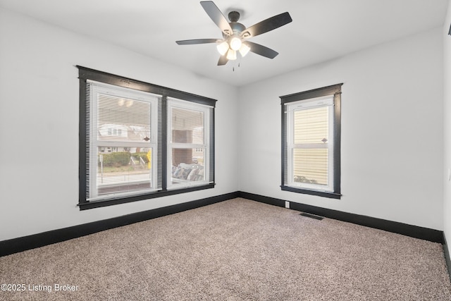 carpeted spare room featuring baseboards, visible vents, and a ceiling fan