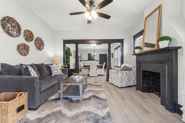 living room featuring a wealth of natural light, light wood-type flooring, a brick fireplace, and ceiling fan