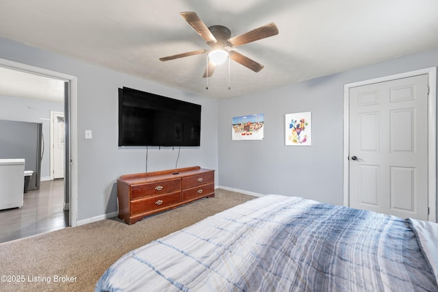 carpeted bedroom featuring freestanding refrigerator, ceiling fan, and baseboards