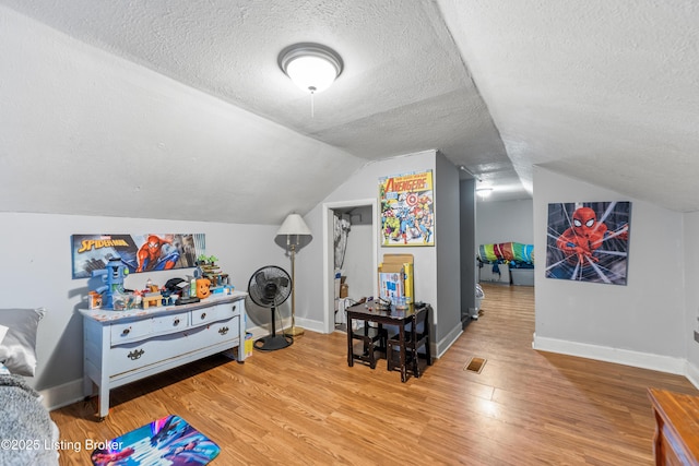 game room with baseboards, visible vents, vaulted ceiling, a textured ceiling, and light wood-type flooring