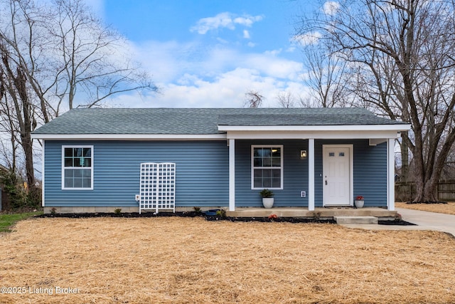 view of front of property with a porch, a shingled roof, and a front yard