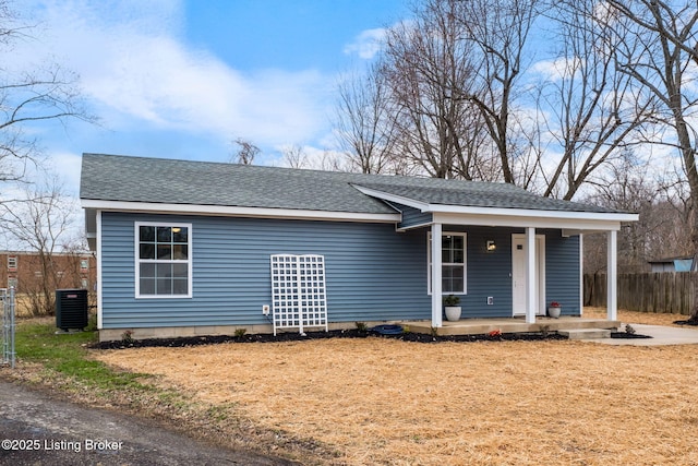 ranch-style home with a shingled roof, central AC, fence, and a porch