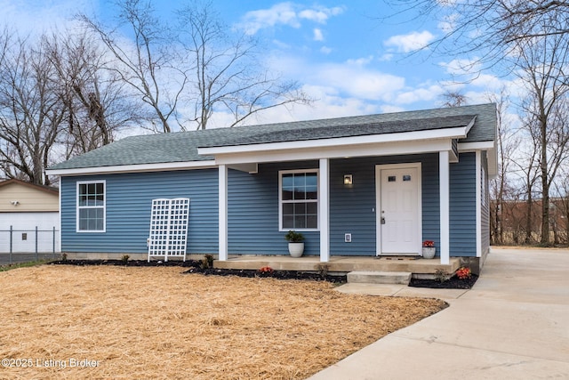 view of front of property featuring a porch, roof with shingles, and an outdoor structure