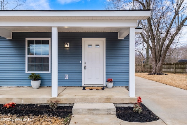 entrance to property featuring covered porch and fence