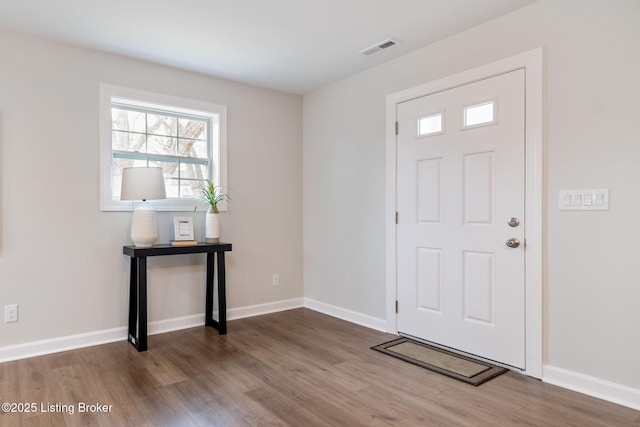 foyer with baseboards, visible vents, and wood finished floors