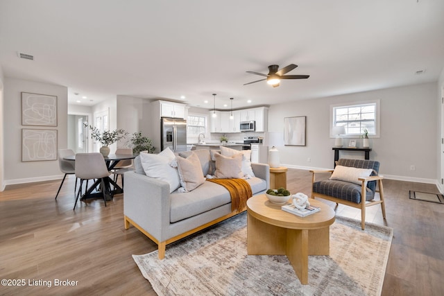 living area with visible vents, baseboards, a ceiling fan, light wood-style flooring, and recessed lighting