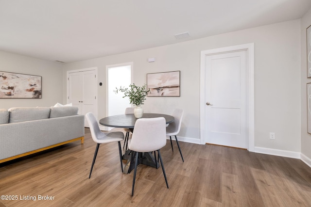 dining space featuring visible vents, baseboards, and wood finished floors