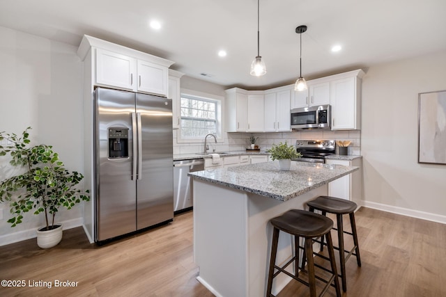 kitchen featuring light wood-type flooring, tasteful backsplash, stainless steel appliances, and a sink