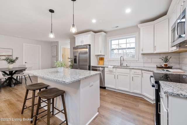 kitchen featuring appliances with stainless steel finishes, decorative backsplash, a sink, and white cabinets