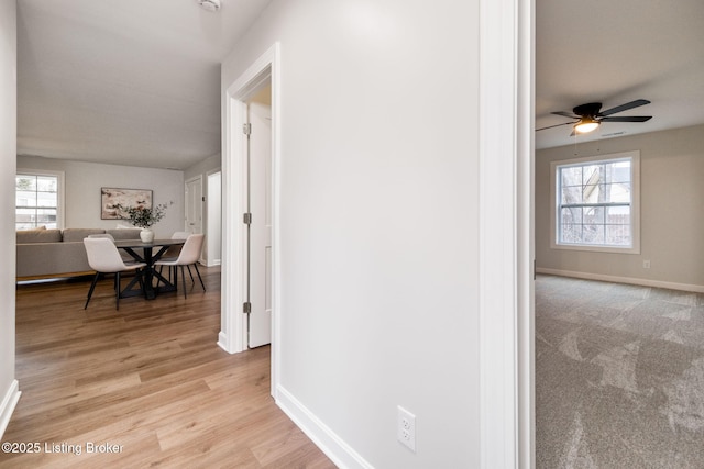 corridor featuring light wood-style floors, plenty of natural light, and baseboards