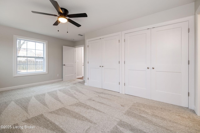 unfurnished bedroom featuring carpet floors, two closets, visible vents, a ceiling fan, and baseboards