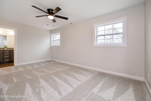 unfurnished bedroom featuring visible vents, baseboards, ensuite bathroom, and light colored carpet