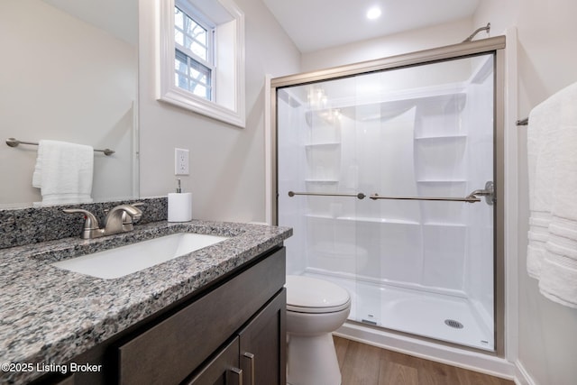 bathroom with vanity, wood finished floors, a shower stall, and toilet