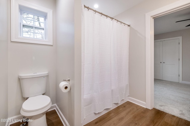 full bathroom with curtained shower, wood finished floors, toilet, and baseboards