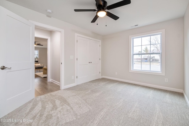 unfurnished bedroom with carpet floors, a ceiling fan, visible vents, baseboards, and a closet