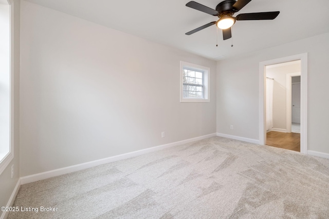 carpeted empty room featuring ceiling fan and baseboards