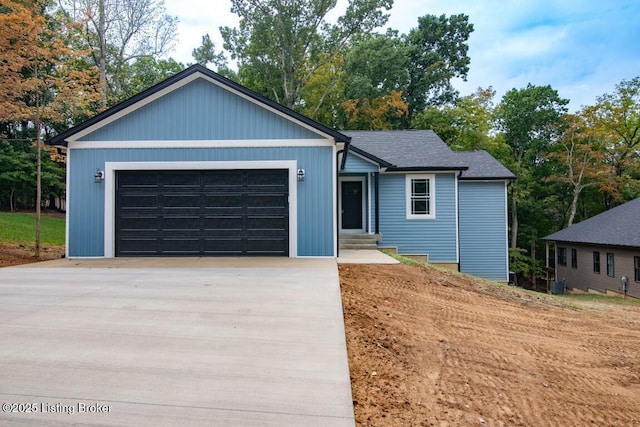 ranch-style home with a garage, a shingled roof, and concrete driveway