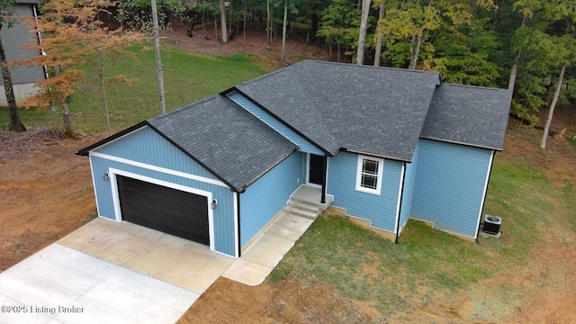 view of front of home featuring a garage, a shingled roof, central AC, and a front yard