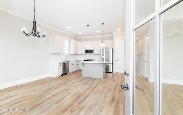 kitchen with crown molding, light wood finished floors, stainless steel appliances, light countertops, and white cabinetry