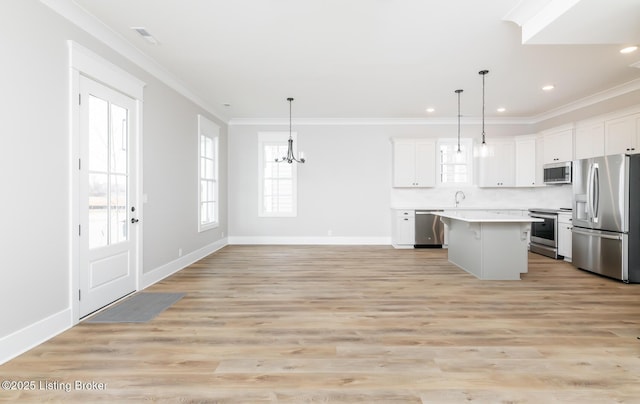 kitchen with a center island, crown molding, light wood finished floors, stainless steel appliances, and light countertops