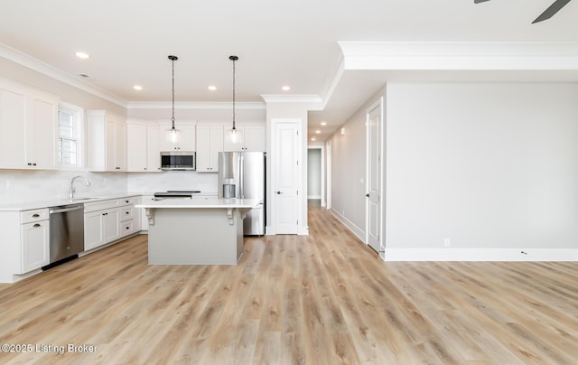 kitchen with a center island, stainless steel appliances, light countertops, white cabinetry, and a sink