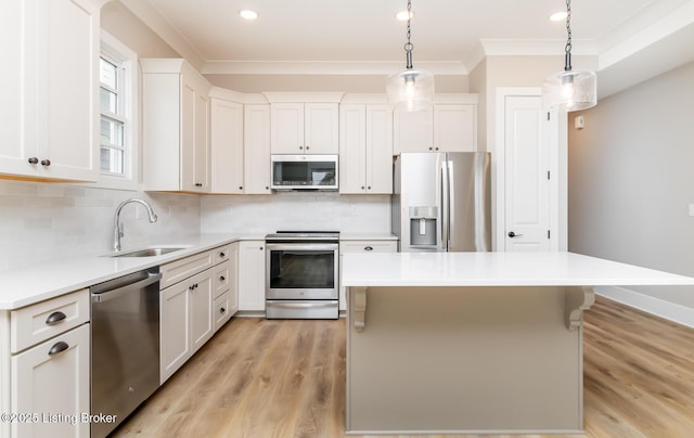 kitchen featuring a center island, stainless steel appliances, crown molding, light wood-type flooring, and a sink