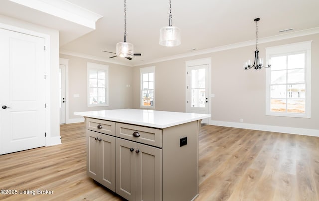 kitchen featuring light wood finished floors, light countertops, hanging light fixtures, gray cabinetry, and ornamental molding