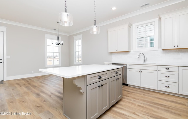 kitchen featuring visible vents, dishwasher, light countertops, crown molding, and a sink