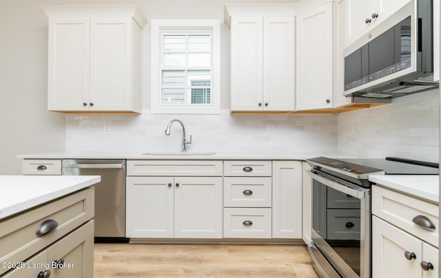 kitchen featuring light wood finished floors, appliances with stainless steel finishes, light countertops, and a sink